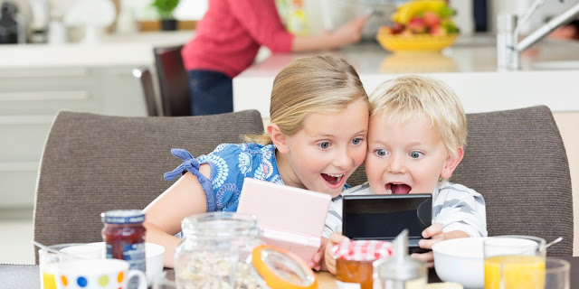 Children playing video games at breakfast