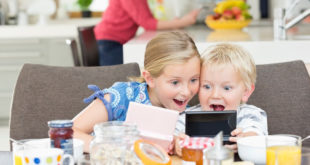 Children playing video games at breakfast